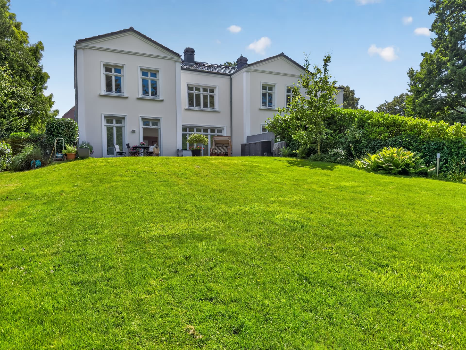 Parkartiger Garten mit weitläufiger Rasenfläche hinter der Villa